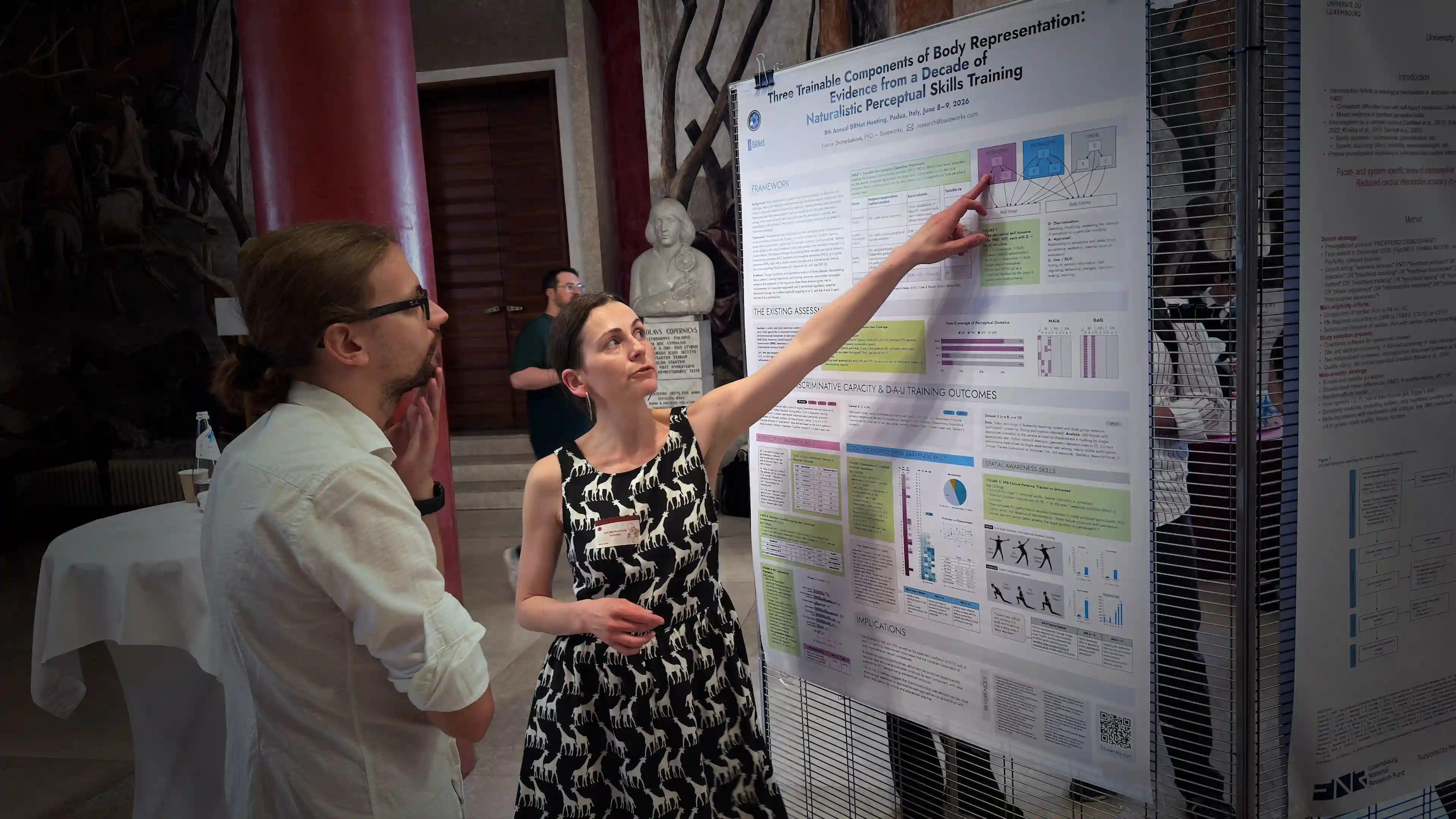 Asia Shcherbakova presenting the Baseworks poster to a researcher at BRNet 2026